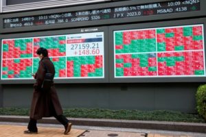 FILE PHOTO: Man walks past an electronic board showing Japan's