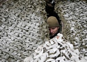 FILE PHOTO: A Ukrainian serviceman camouflages a self propelled howitzer